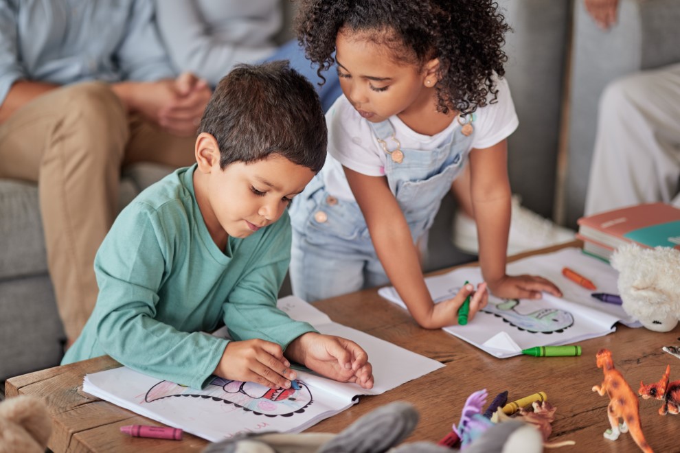 Niños dibujando con papel y colores en compañía de sus padres
